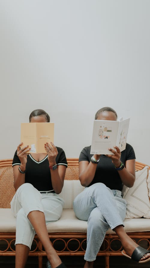 Women in Black Shirt Sitting on a Sofa while Reading a Book