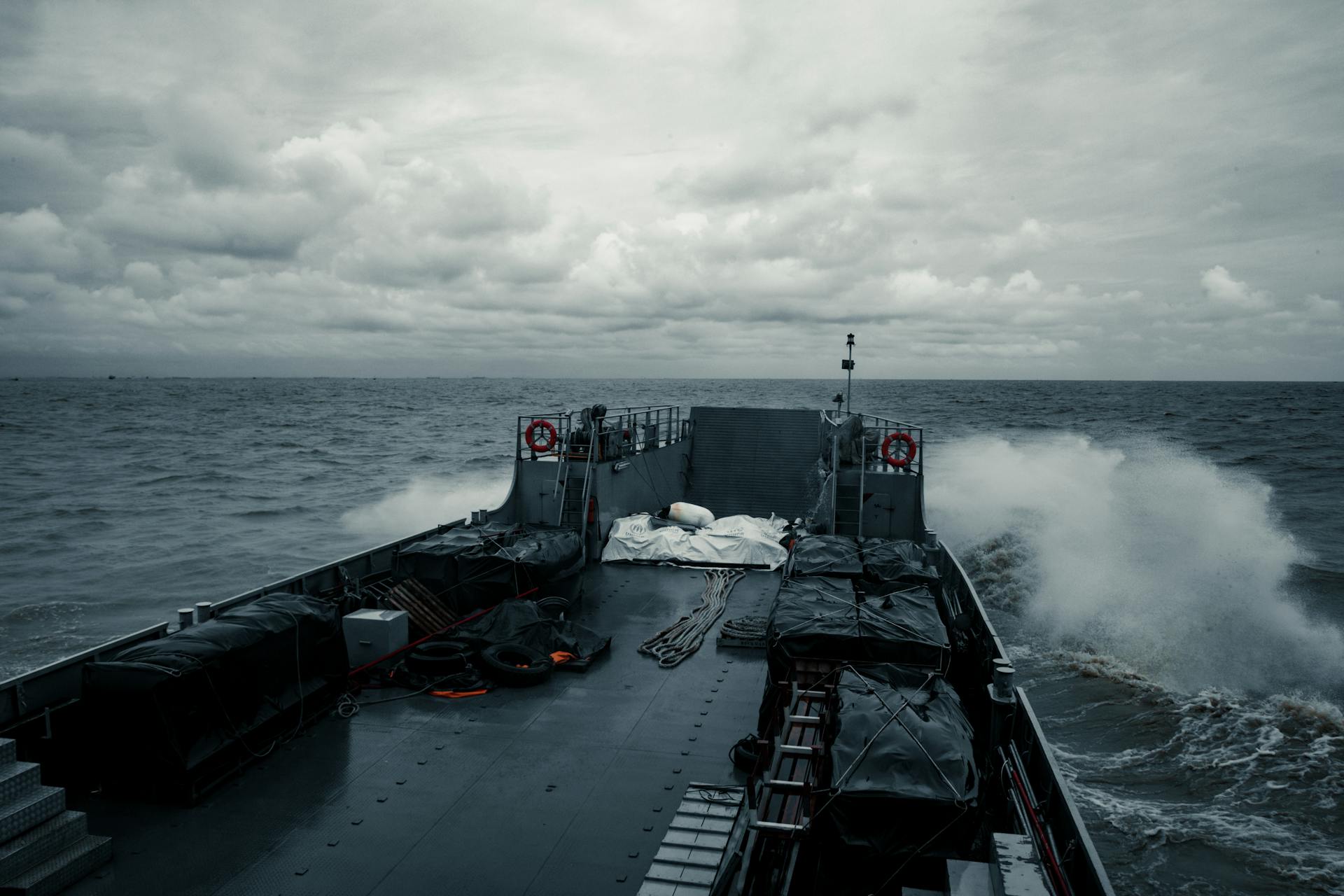 A military ship cruises through choppy ocean waters under a cloudy sky, showcasing naval power.