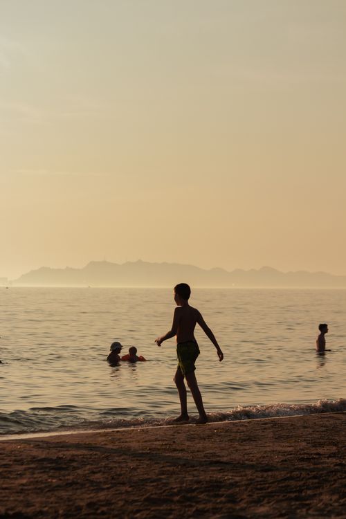 Free A peaceful silhouette of a child walking along Durrës beach, Albania, with a calm sea backdrop at sunset. Stock Photo