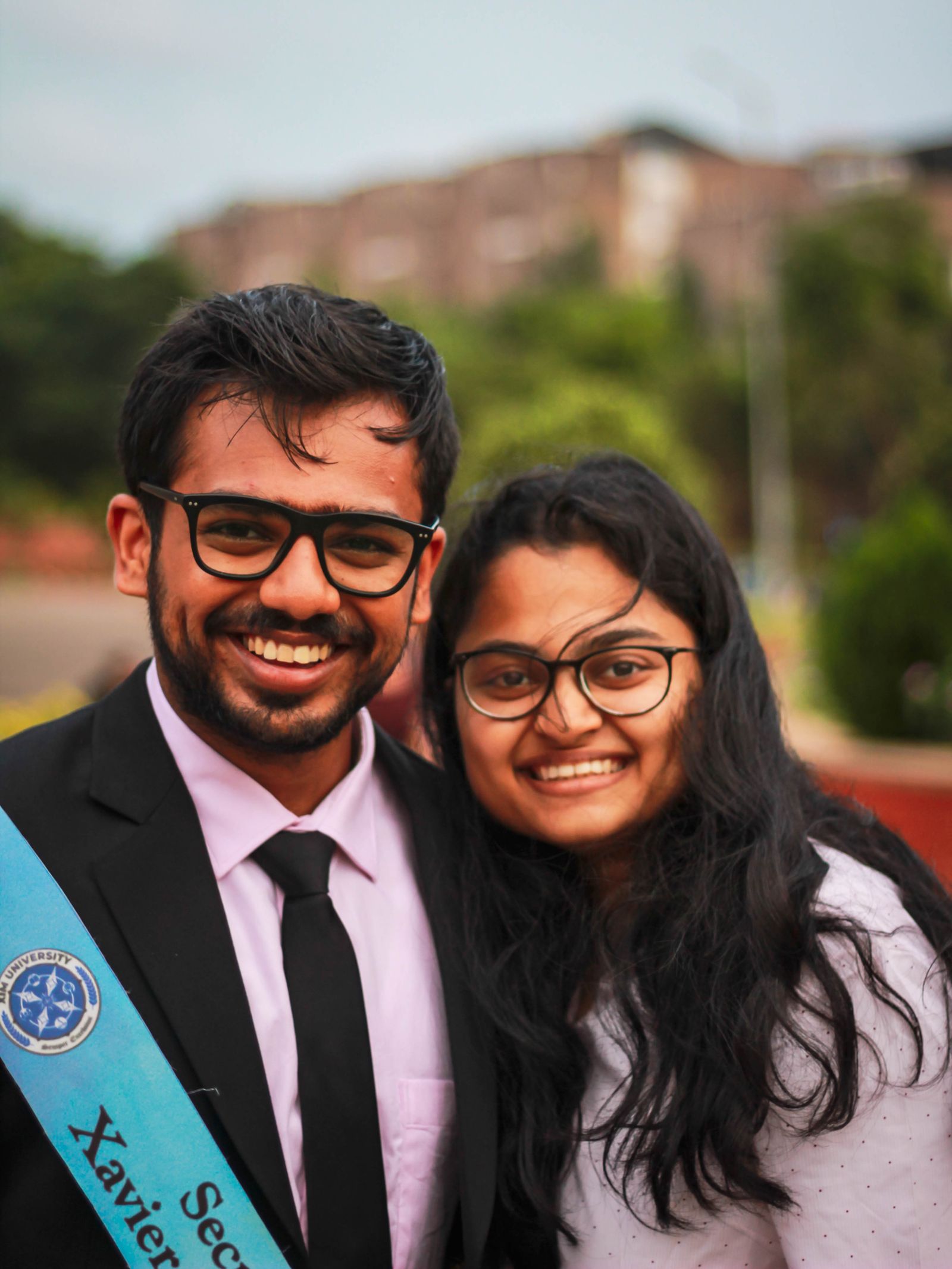 Two graduates in caps and gowns smiling outdoors