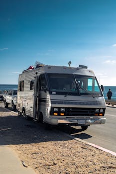 Explore coastal roads with a classic RV under a clear blue sky, perfect for adventurous road trips.