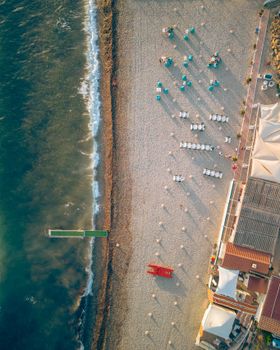 Drone shot of a sandy beach with umbrellas and lounge chairs during summer.