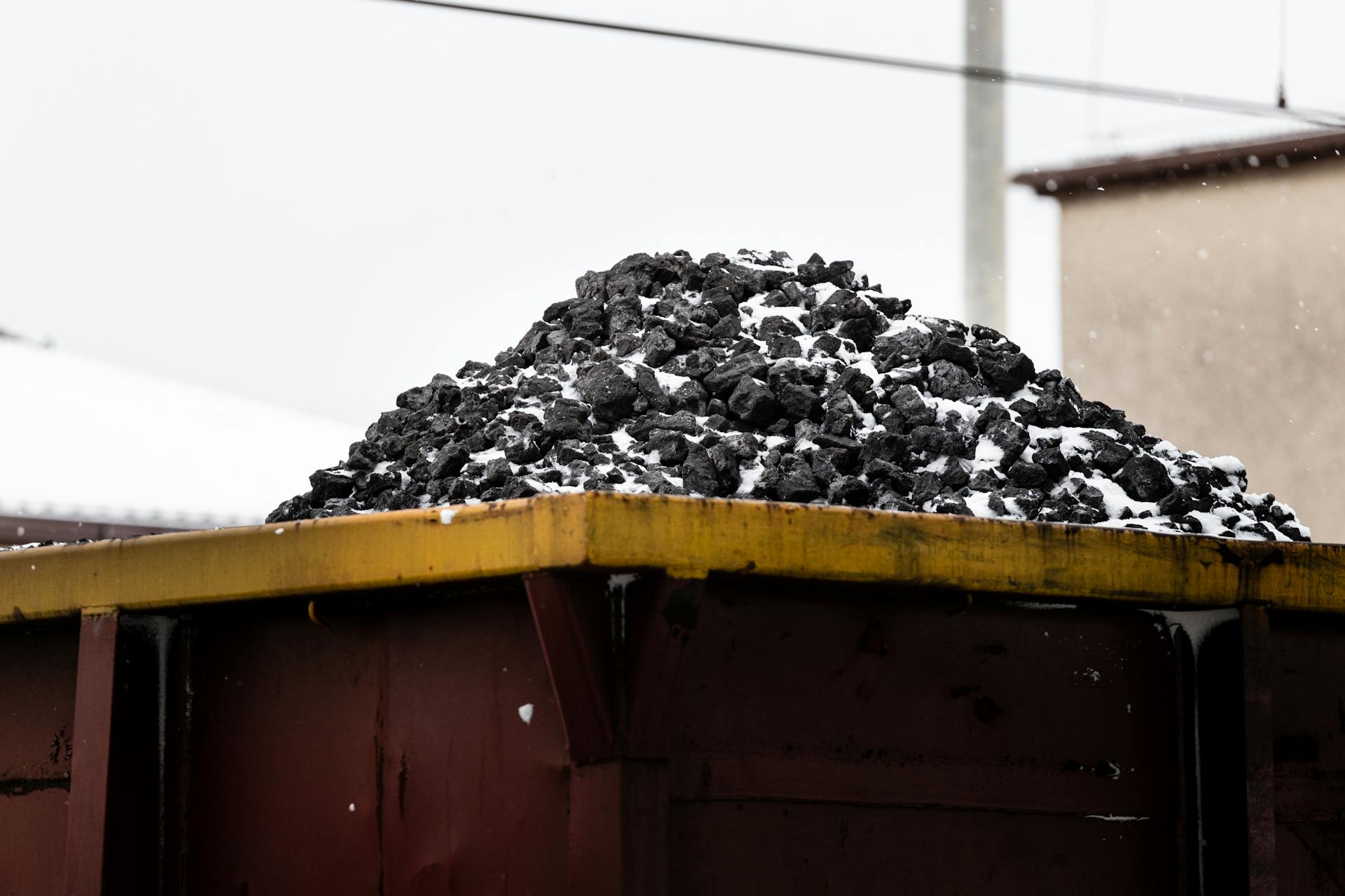 A heap of coal on a freight train car covered with snow, symbolizing transport and industry.