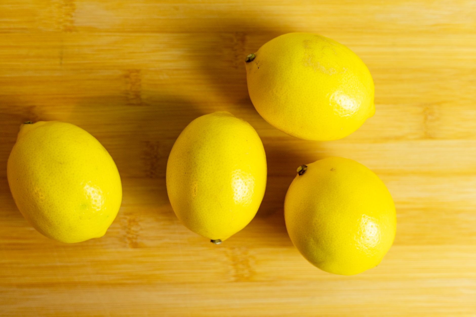Vegan lemon cheesecake with glossy lemon curd topping in a clear dish