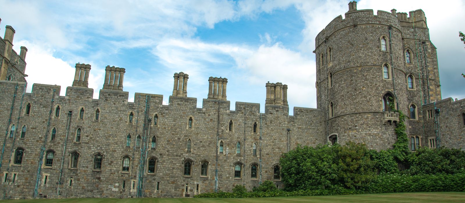 Windsor Castle's historic stone facade under a vibrant blue sky, showcasing its iconic turrets.