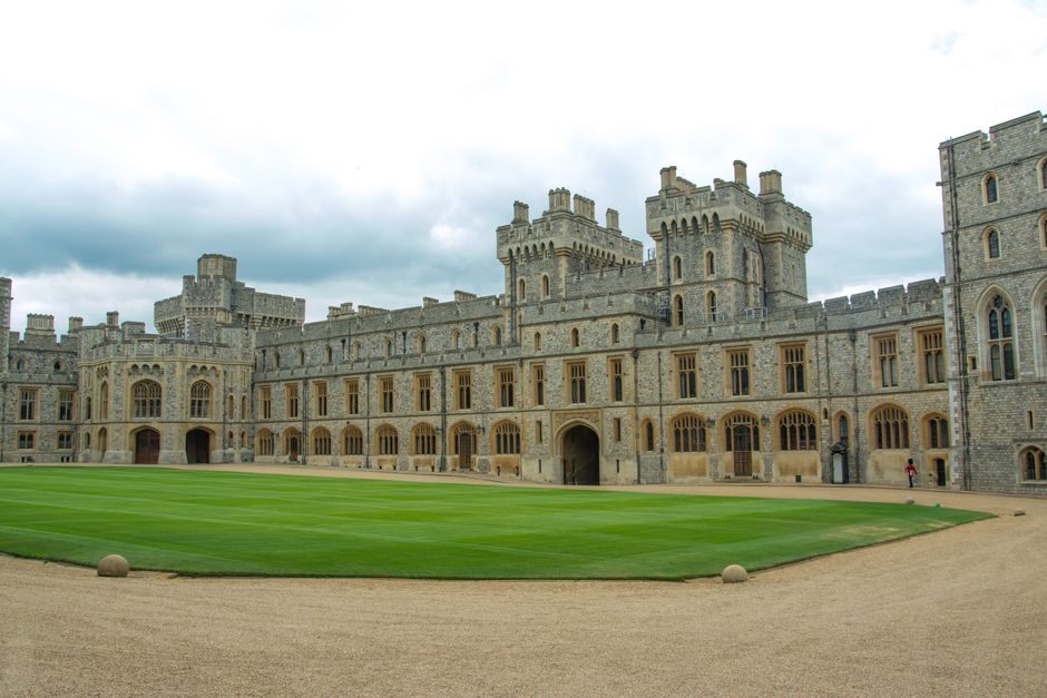 Historic view of Windsor Castle's grand architecture and courtyard on a cloudy day.
