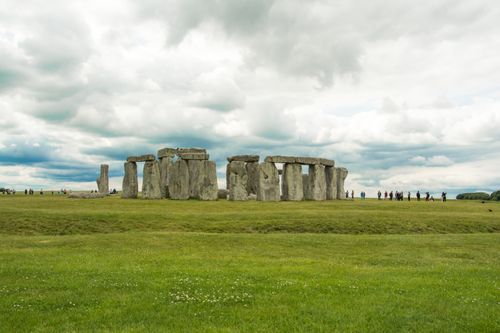 Free Stonehenge with tourists under cloudy skies showcasing the iconic landmark in England. Stock Photo
