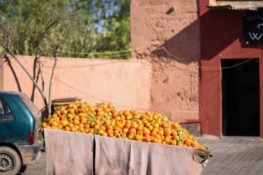 A cart filled with bright oranges on a sunny street in Marrakesh, Morocco, showcasing vibrant local culture.