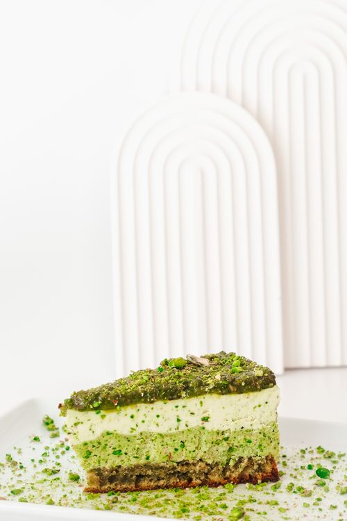 Free Delicious pistachio slice with textured layers served on a white plate, perfect for dessert lovers. Stock Photo