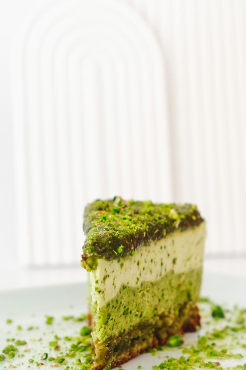 Free Close-up of a luscious matcha cake slice with creamy layers, sprinkled with green topping. Stock Photo