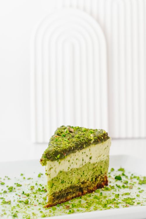 Free Close-up of a green pistachio layer cake slice with decorative backdrop. Stock Photo