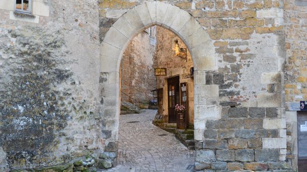 Charming medieval stone alley with an archway and rustic building facade.