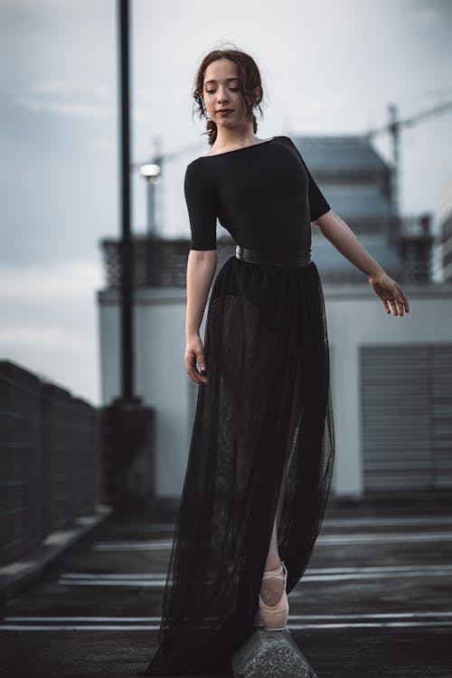 A Ballerina Wearing Black Tutu Dress Dancing on the Street