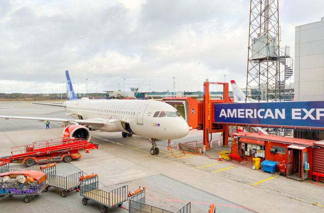 Aircraft docked at Stockholm Arlanda Airport gate with ground crew and equipment. — arriving in Stockholm