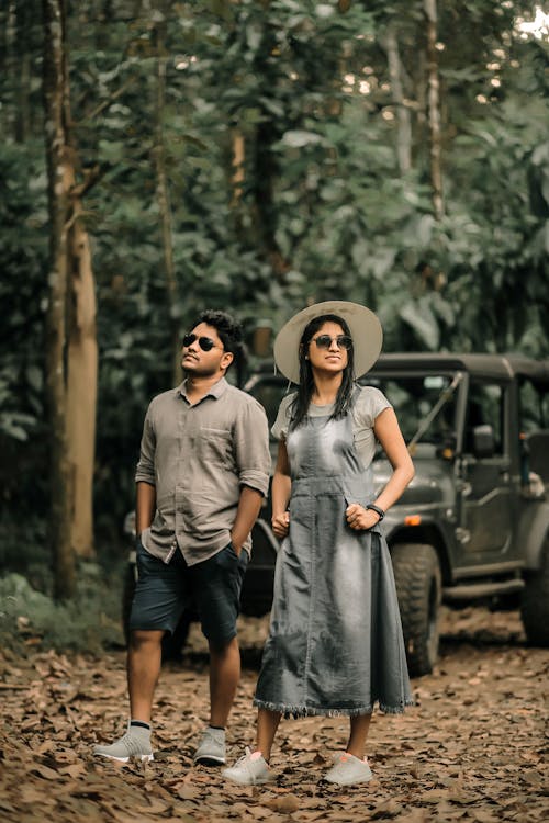 A Couple Standing in the Forest Near 4x4 Gray Car 