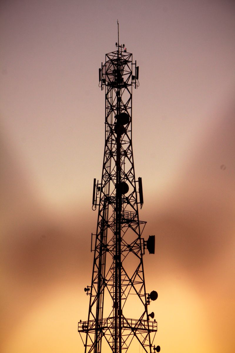 Telecom tower silhouette against a dramatic golden hour sky
