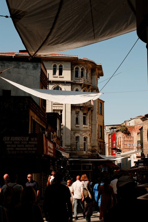 Free A lively street scene with people walking among historical buildings under a blue sky. Stock Photo