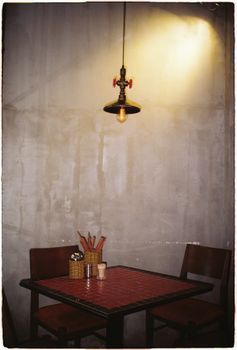 A quaint cafe setting featuring a vintage table and pendant lamp against a rustic wall.