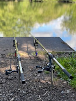 Pair of fishing rods set up by a peaceful lake in the UK, ready for a serene fishing day.