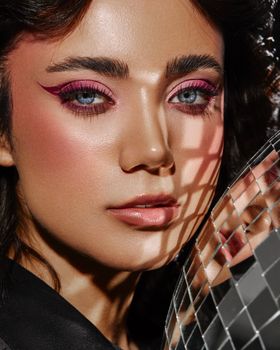 Elegant close-up portrait of an adult woman with striking eye makeup and mirror reflections.