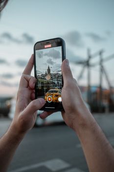 Hands holding a smartphone capturing a video of Istanbul's iconic Galata Tower during sunset.