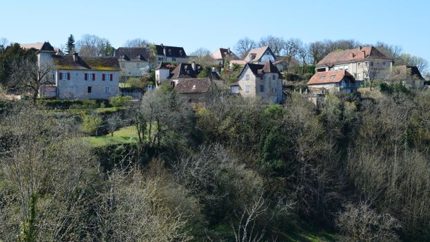 Picturesque view of a countryside village with traditional stone houses and lush foliage.