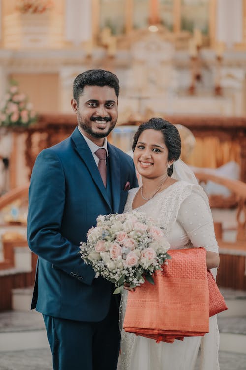 Portrait of Smiling Newlyweds with a Bouquet in a Church