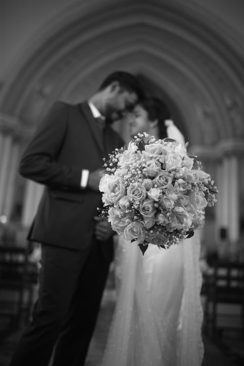 Grayscale Photo of a Man and a Woman Holding Bouquet of Flowers