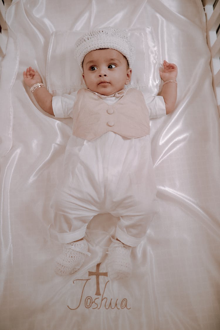 A Cute Baby Boy Lying Down While Wearing Onesie