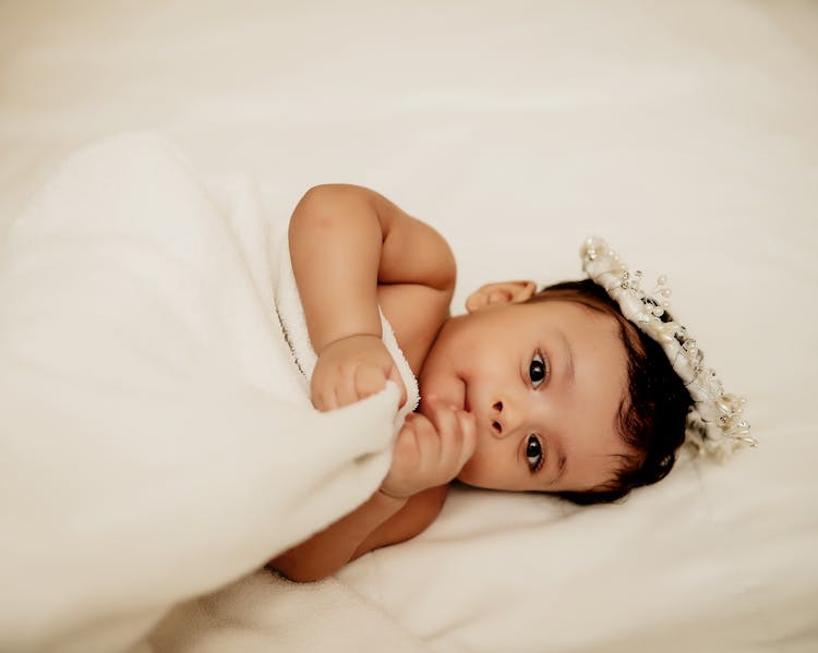 A Baby Lying Down On The Bed 