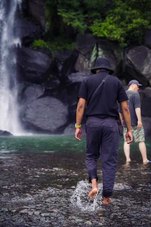 A Man Walking Near the Waterfall