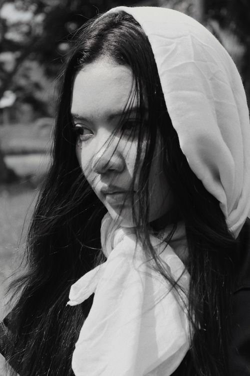 Free Black and white portrait of a woman wearing a headscarf, looking contemplative outdoors. Stock Photo