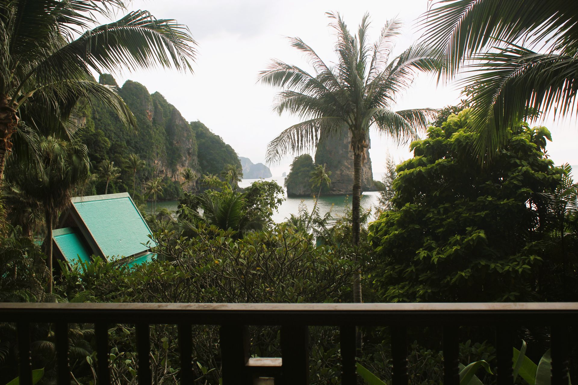 Experience a serene tropical island setting with palm trees and distant rock formations.