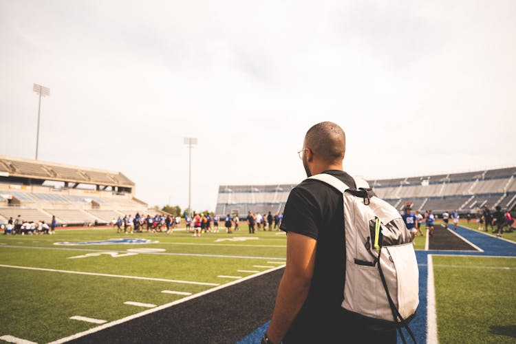 A Man With Backpack Watching American Football