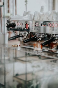 A close-up of a professional coffee machine brewing espresso in an indoor cafe setting.