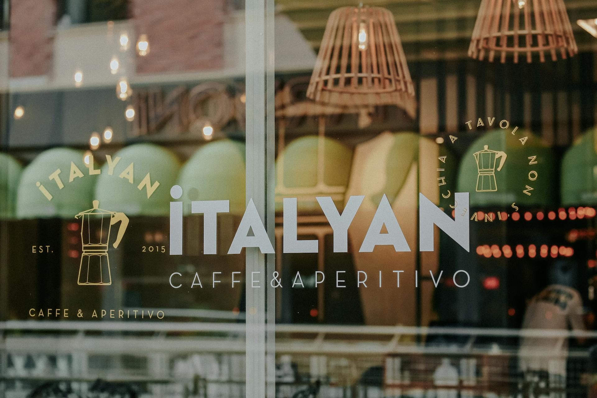 Close-up of glass window with Italian cafe branding and reflections.