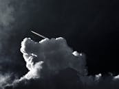 这张引人注目的照片展示了一架飞机在黑暗而引人注目的云层中留下了飞行轨迹