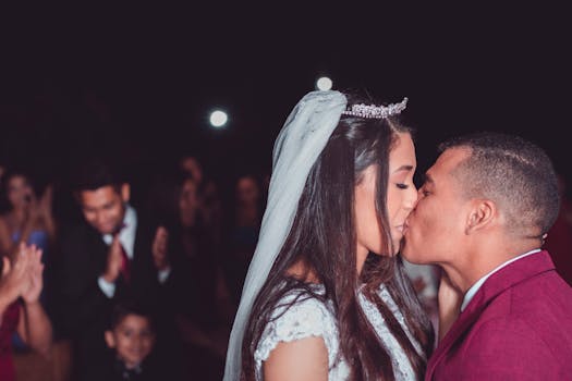 Bride and groom share a romantic kiss during their wedding ceremony at night.