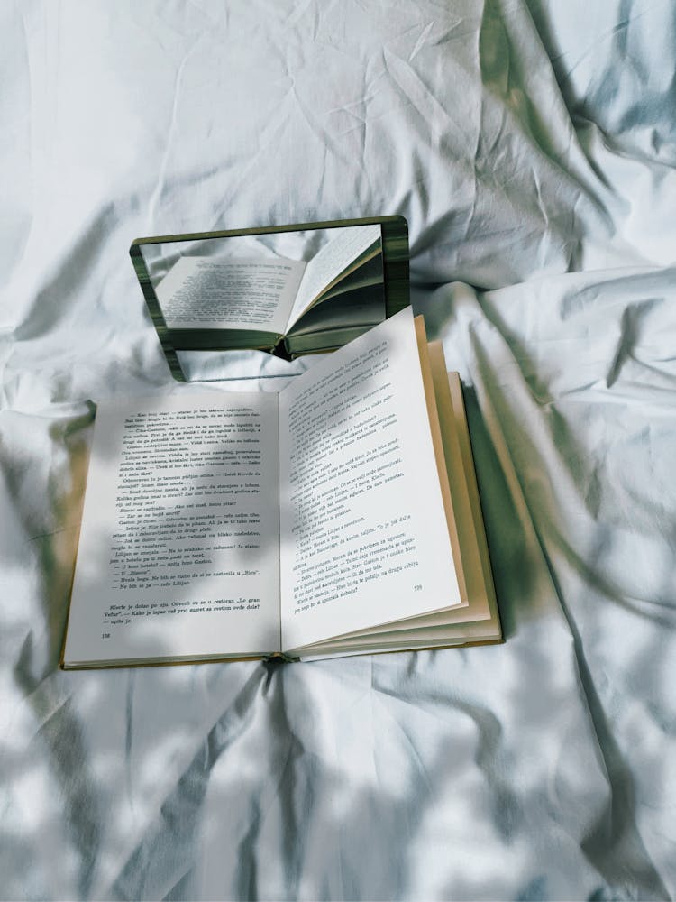 A Book And Mirror On The Bed 