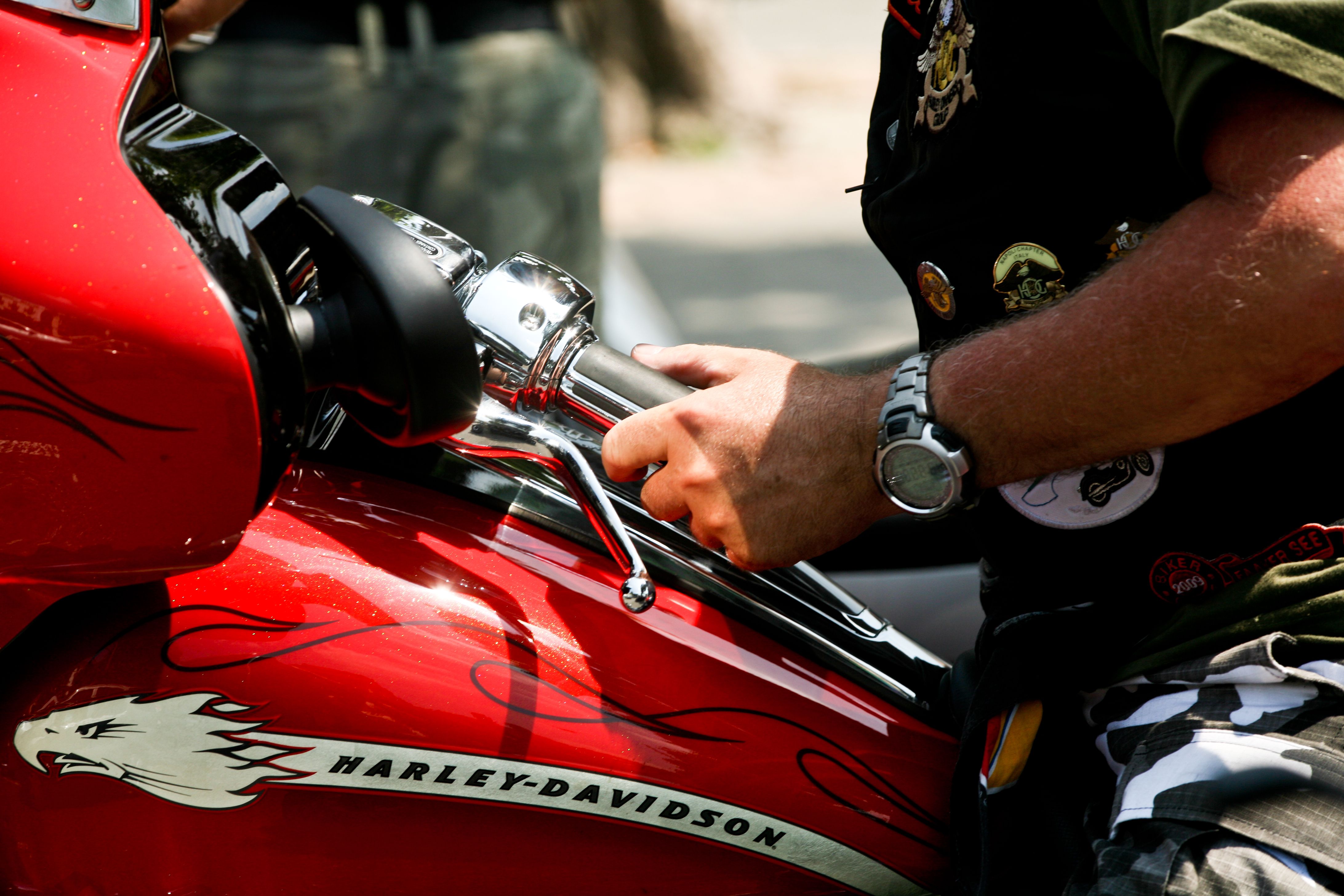 Man riding a Harley-Davidson motorcycle, featuring close-up of handlebars and vibrant red paint.