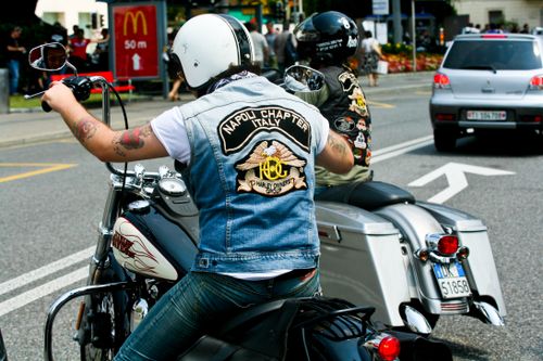 Free Motorcycle enthusiasts in denim vests riding through city traffic. Stock Photo