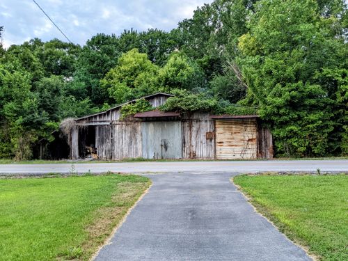 Free Charming old farmhouse surrounded by lush forest and vibrant grass in Kentucky. Stock Photo
