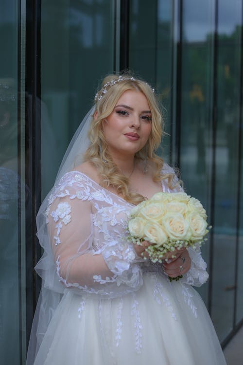 Bride in White Wedding Dress Holding a Bouquet of Flowers