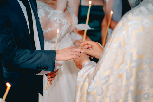 A couple exchanges rings during a traditional wedding ceremony in a church setting.