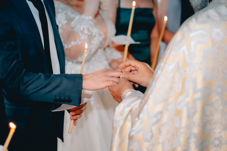 A couple exchanges rings during a traditional wedding ceremony in a church setting.