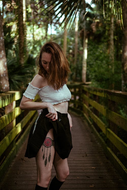 A Woman in White Off Shoulder Top Standing on the Bridge