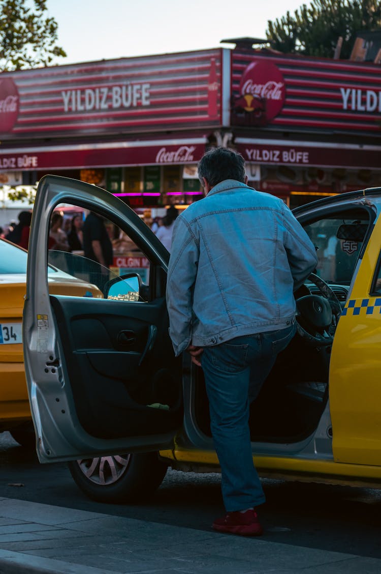 A Man In A Denim Jacket Riding A Taxi