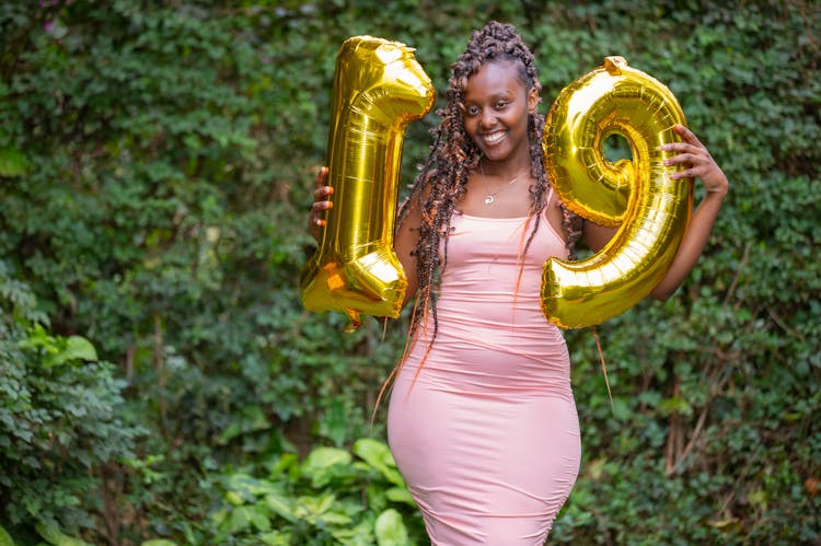 A Woman In Pink Dress Holding Gold Balloon