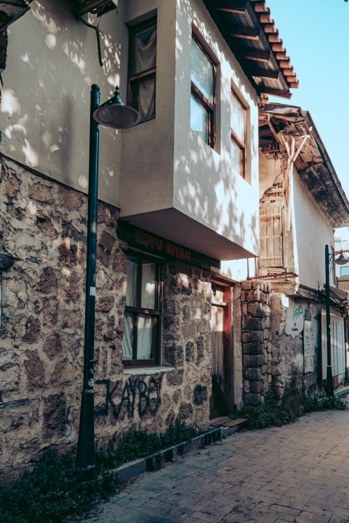 Free A picturesque old stone building with wooden windows in a sunlit alley. Stock Photo