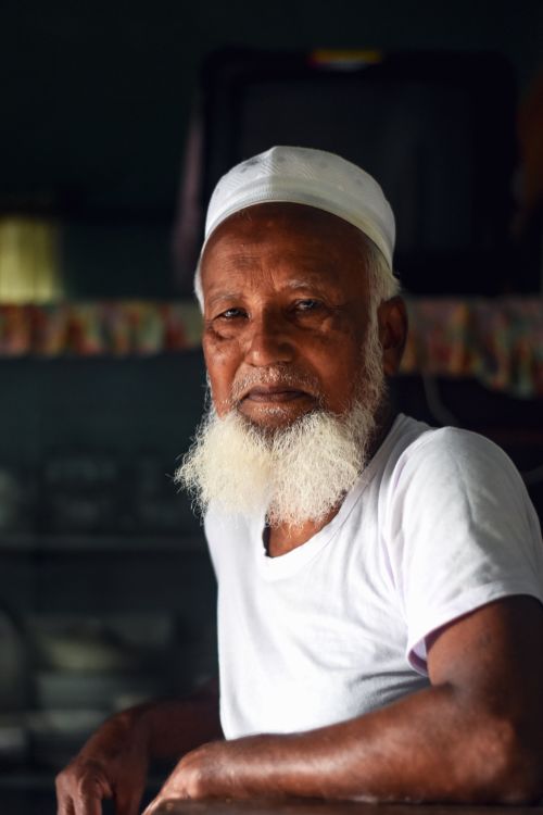 Free Elderly man with a white beard wearing a cap and shirt, posing indoors. Stock Photo